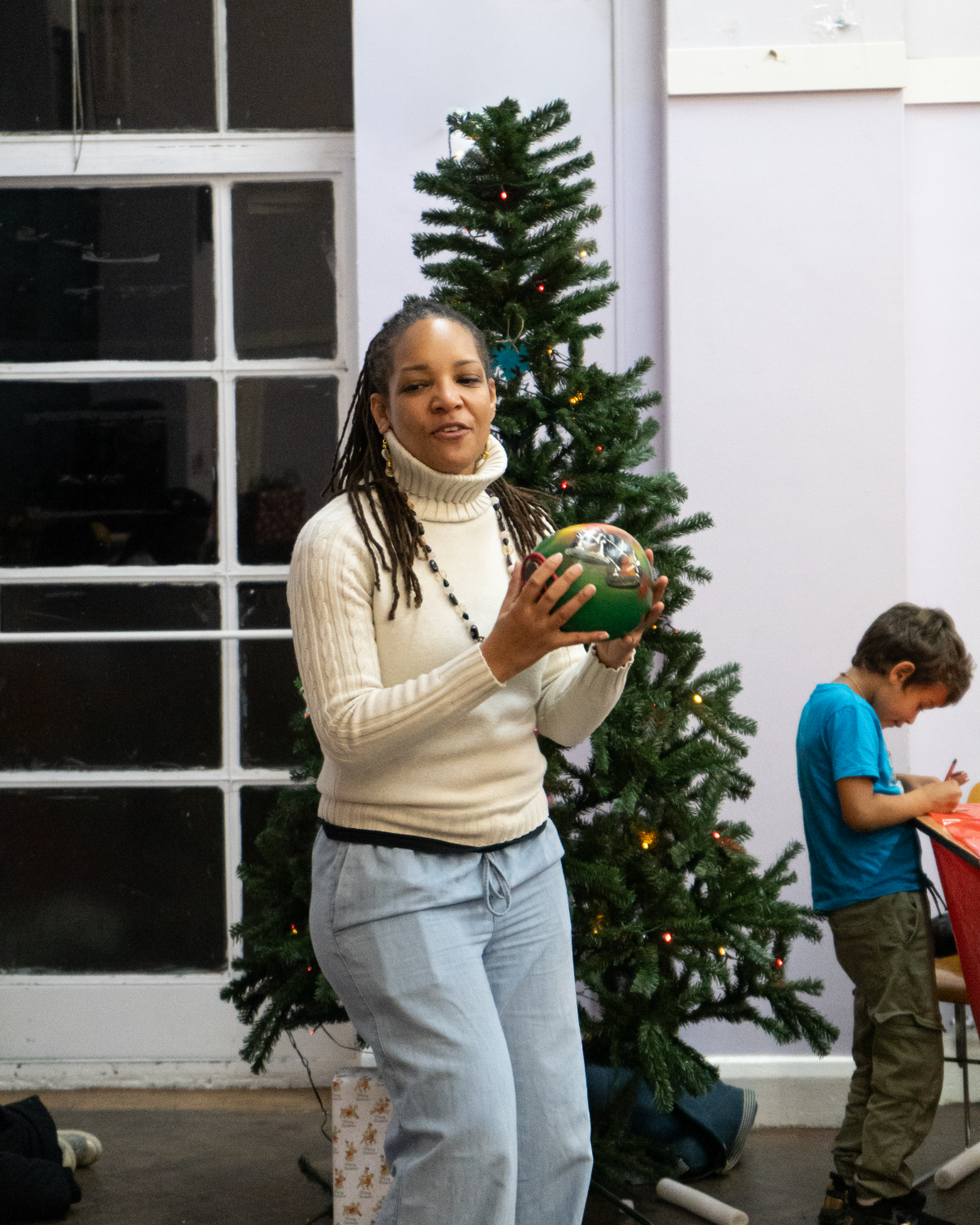 A storyteller holding a painted globe beside the Christmas tree